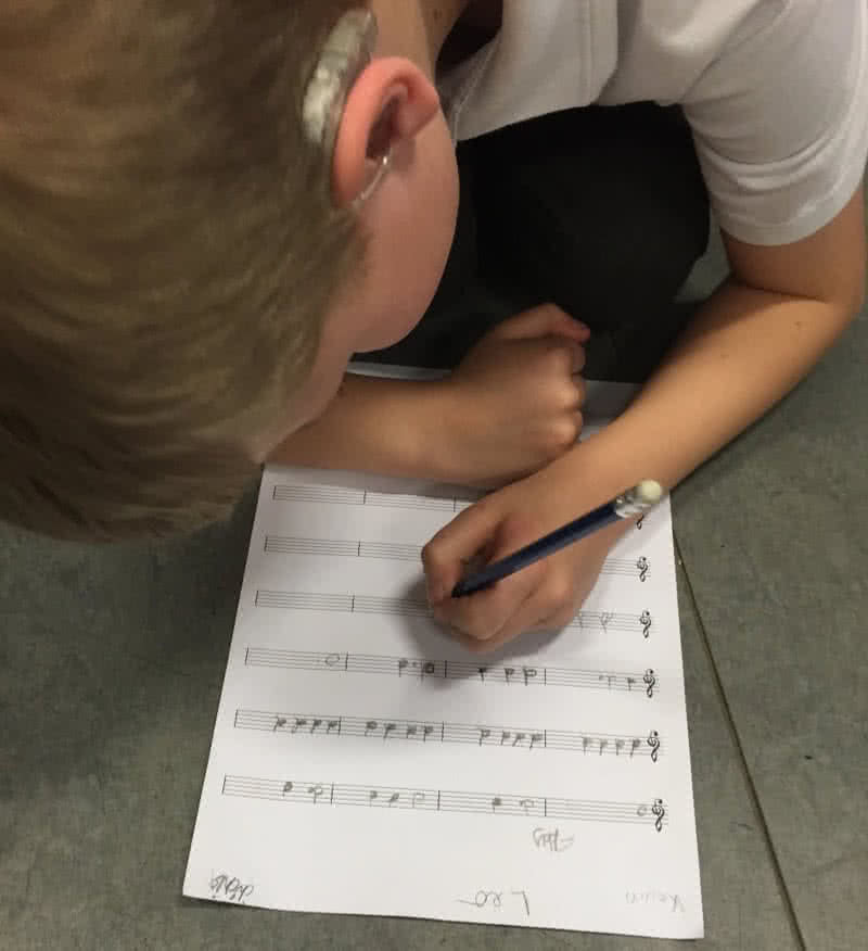 A student writes music on paper